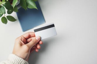 Student hält eine moderne Kreditkarte neben Reisepass und Weltkarte für das Jahr 2025.