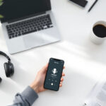 Schreibtisch mit Kopfhörern, Smartphone mit Podcast-App, Finanzzeitung und Kaffeetasse als Symbol für Finanzpodcasts in Deutschland 2025.