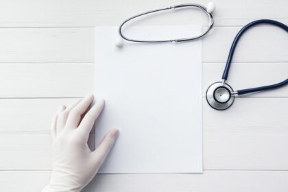 Hand hält Patientenverfügung neben Stethoskop auf Tisch – Symbol für selbstbestimmte medizinische Entscheidungen.