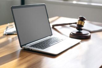 Ein Laptop, ein Richterhammer und ein Testament auf einem Schreibtisch als Symbol für das digitale Testament in Deutschland.